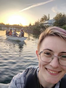 A selfie of a person in a row boat and three smiling people in another in the background